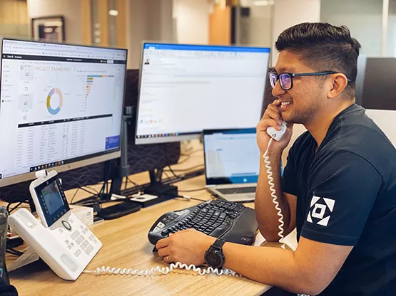 A Servcorp team member provides real-time IT support over the phone while monitoring multiple systems