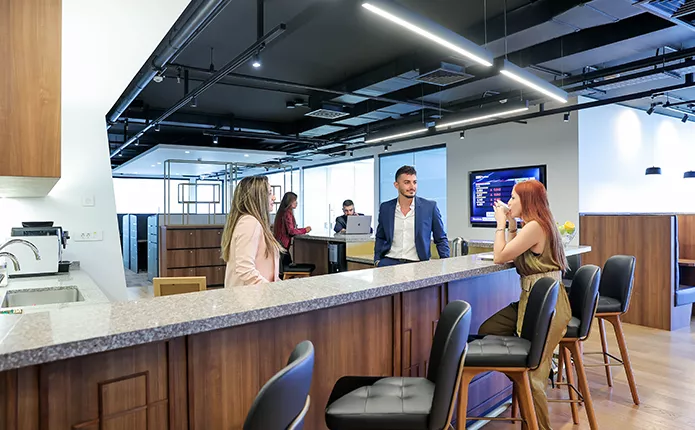 Coworking Space at Qubic Square with people networking and collaborating in a fully stocked kitchen.